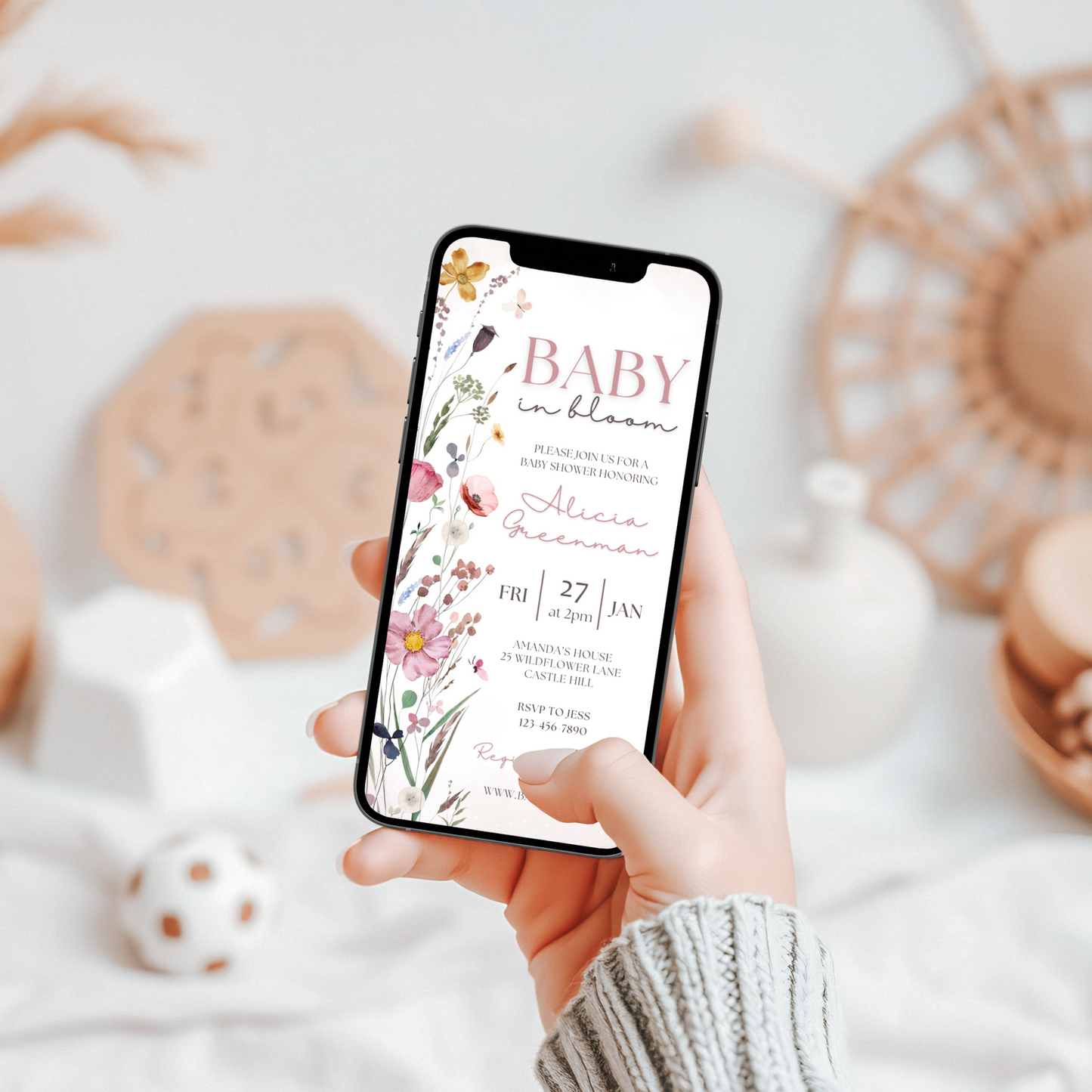 editable baby in bloom invitation template being shown on a mobile screen which is being held in a women's hand.